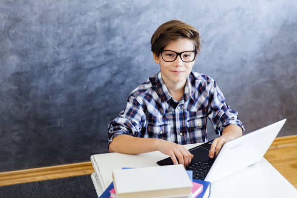 Teenage boy working on laptop at home - Fotó, kép