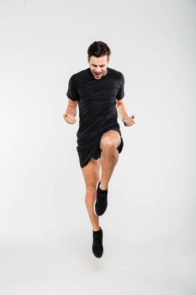 Full length portrait of a cheerful pleased sportsman jumping - Фото, зображення