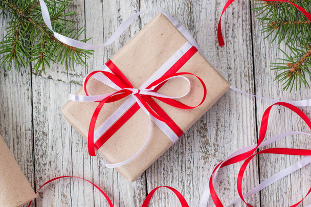 Packing Christmas presents in kraft paper with red and white ribbons - Foto, afbeelding