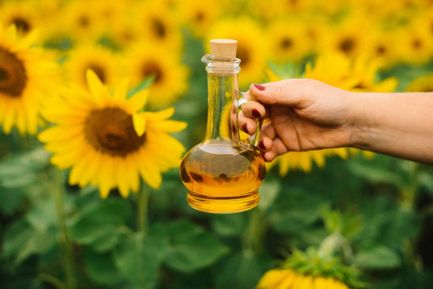Sunflower oil in glass bottle  with sunflower field on the backg - Photo, Image