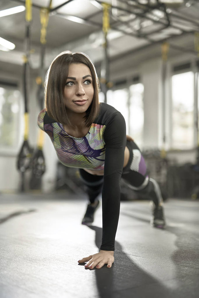 Sportive girl does exercise in gym - Foto, afbeelding