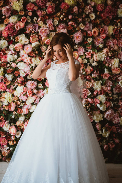 schöne Braut auf dem Hintergrund einer Wand aus Blumen - Foto, Bild