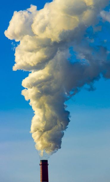 Труба завода выбрасывает вредные вещества в атмосферу. Крупный план на фоне неба
 - Фото, изображение
