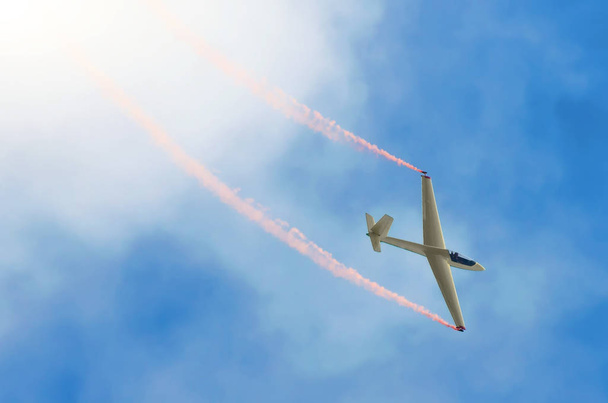 Глайдер самолета летит высоко в небе со следами красного дыма
. - Фото, изображение