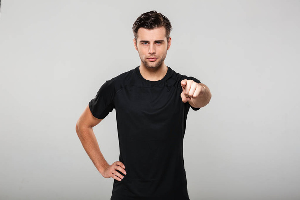Portrait of a young confident sportsman pointing finger - Foto, imagen