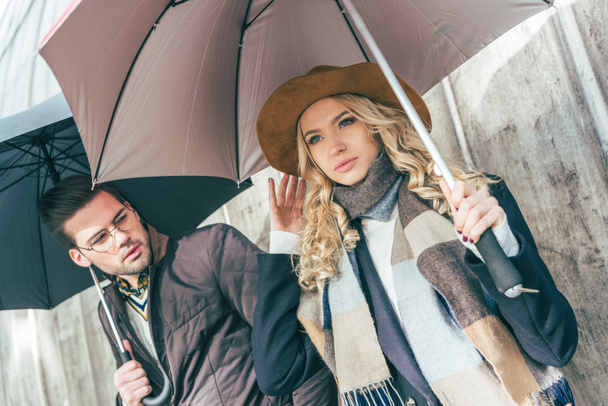 stylish young couple with umbrellas - Foto, imagen