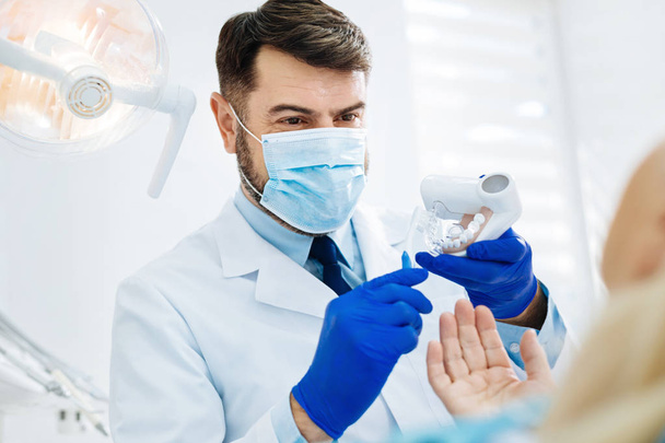 Close up of positive dentist holding false teeth in hands - Zdjęcie, obraz