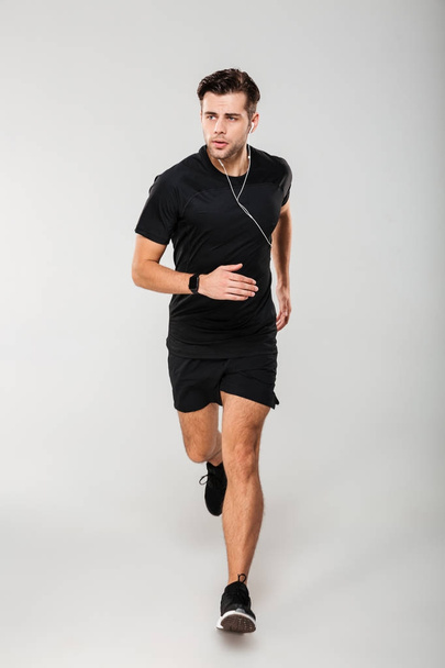 Full length portrait of a fit man athlete in earphones - Photo, image