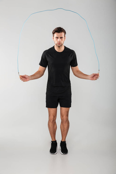 Strong young sports man jumping with skipping rope - Fotó, kép