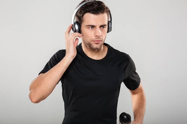 Portrait of a serious handsome sportsman listening to music - Foto, imagen