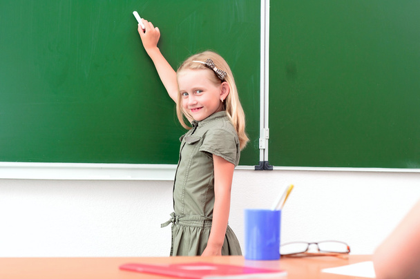 Schoolgirl writing on a blackboard - Фото, зображення
