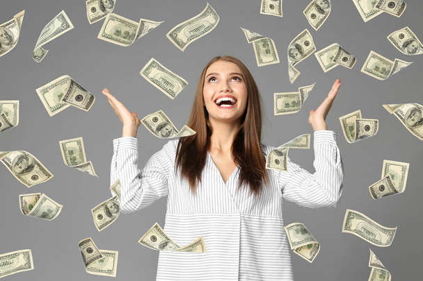 Young woman with money on grey background - Foto, afbeelding