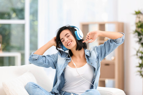 Young woman listening to music through headphones at home - Фото, зображення