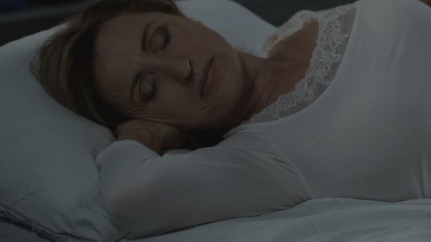 Woman peacefully lying on comfortable bed, healthy sleep, orthopedic mattress - Filmati, video