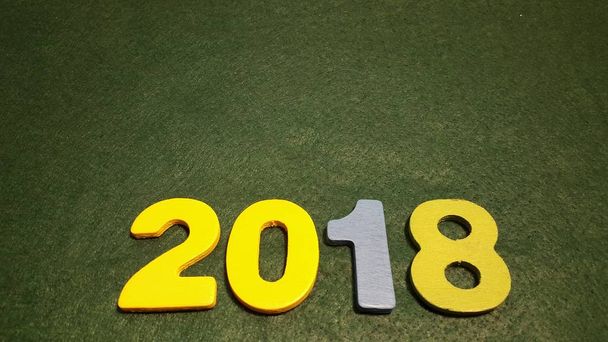έγχρωμες φιγούρες να σχηματίσουν τον αριθμό 2018 σε πράσινο φόντο - Φωτογραφία, εικόνα