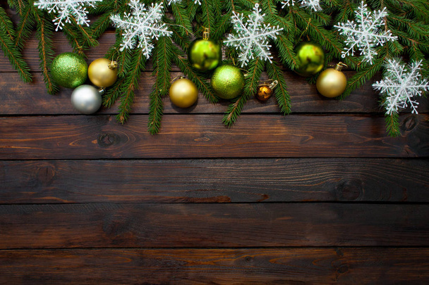 Green living spruce branches on a dark wooden background. New Year background with beautiful balls and white snow. Top view - Photo, Image