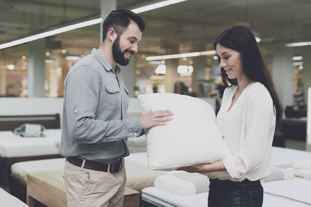 A couple in a large store of beds and mattresses chooses pillows. They examine several variants of pillows - Фото, зображення