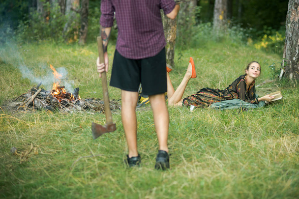 男は森でたき火で斧を保持します。 - 写真・画像