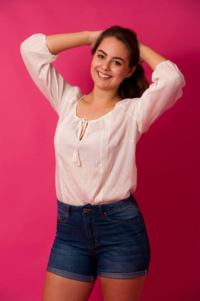 Cute young woman in light summer clothes over pink background - Fotó, kép