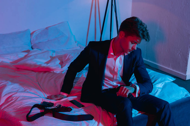 businessman sitting on bed in dark room - Foto, afbeelding