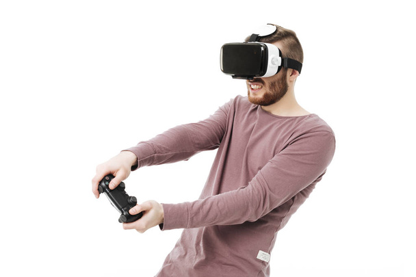 Молодий чоловік використовує окуляри віртуальної реальності та грає у відеоігри на білому тлі. Хлопчик з джойстиком в руках в окулярах візуальної реальності ізольовані
 - Фото, зображення
