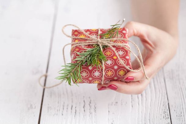 Close up of female hands holding a small christmas gift wrapped with twine. Small gift in the hands of a woman indoor. Shallow depth of field with focus on the little box - Fotografie, Obrázek