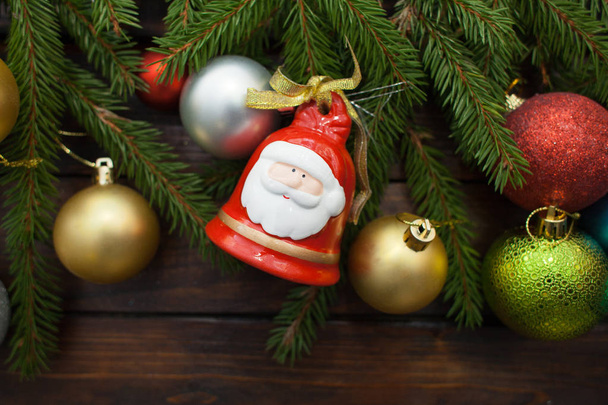 Rami di abete rosso vivo verde su uno sfondo di legno scuro. Sfondo Capodanno con palloncini multicolori e campane nell'idea di Babbo Natale. Vista dall'alto
 - Foto, immagini