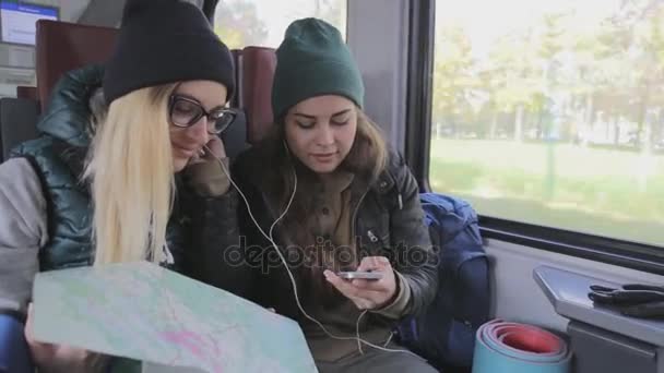 Happy girlfriends travelers listen to music in train - Footage, Video