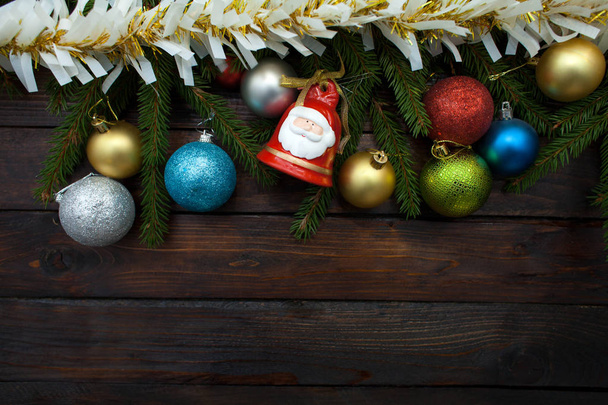 Ramos de árvore de Natal verde em um fundo de madeira escura. Fundo de Ano Novo com bolas multicoloridas e ouropel de ouro e sino. Vista superior
. - Foto, Imagem