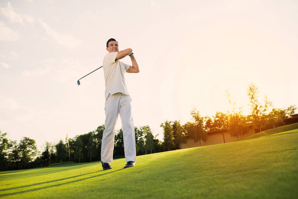 Wielki cios. Człowiek w białym garniturze gra w golfa. on jest zadowolony z jego cios - Zdjęcie, obraz