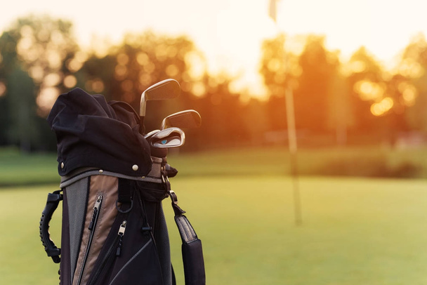 Close up. A bag for golf clubs with golf clubs on the sunset background - 写真・画像