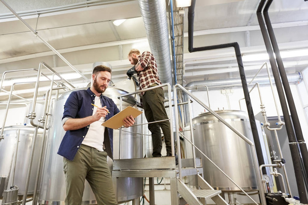 men with clipboard at brewery or beer plant - Photo, Image