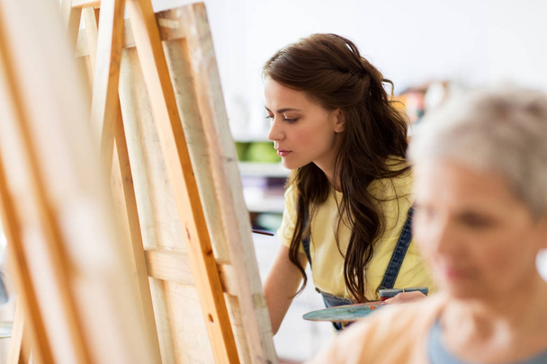 student girl with easel painting at art school - Foto, Imagen