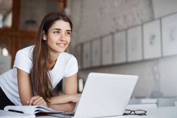 Portrait of confident young female entrepreneur standing near laptop computer looking forward into her future millionaire house. - Foto, Imagen