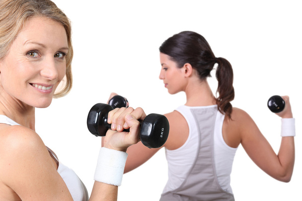 Two women lifting weights together - Foto, afbeelding