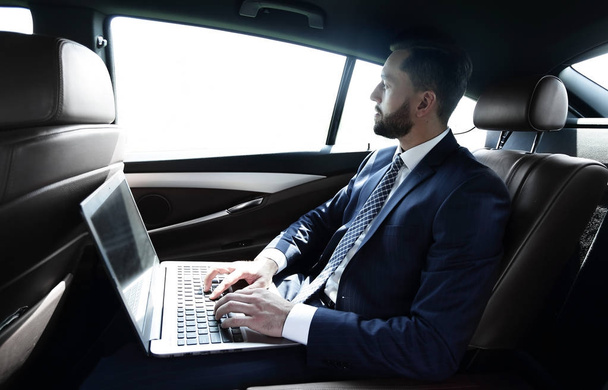 Businessman working with laptop sitting in car - Zdjęcie, obraz