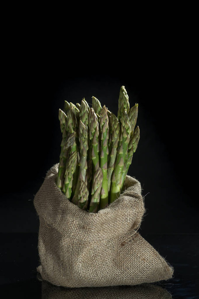 Fresh uncooked green asparagus on black background - Foto, Imagem