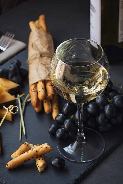 Cheese plate served with crackers, grapes and glass of white win - Photo, image