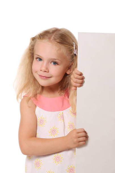 little girl peeks out from behind a white sheet on a white backg - Foto, afbeelding