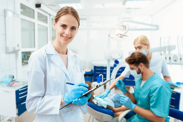A nurse posing against a background of dentists who treat a girl's teeth. - Valokuva, kuva