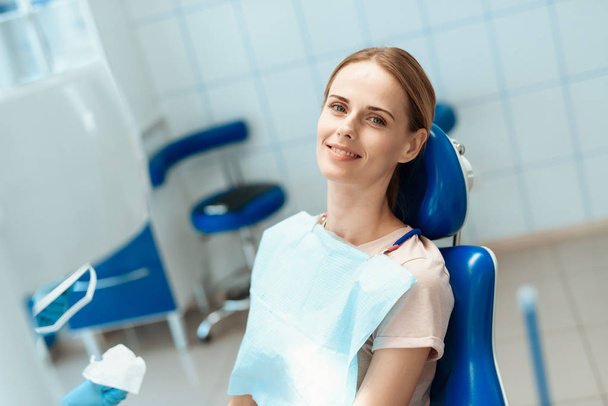 Woman posing in blue dental chair and smiling - Foto, imagen