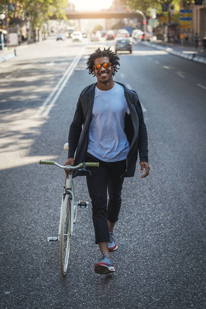 Handsome afro man walking with his bike. - Zdjęcie, obraz