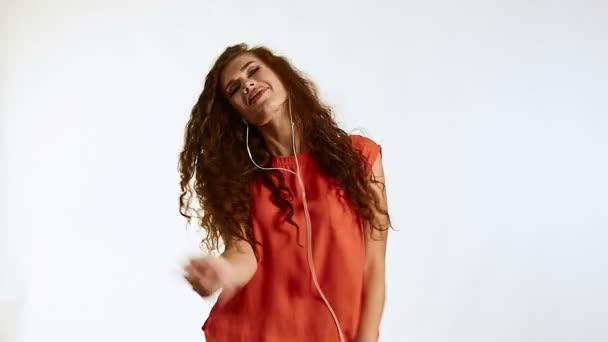 brünette Frau Modell mit lockigem Haar Musik hören auf weißem Hintergrund im Studio - Filmmaterial, Video