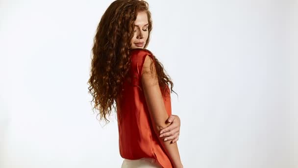 Brunette vrouw met krullend haar poseren op witte achtergrond in de studio - Video
