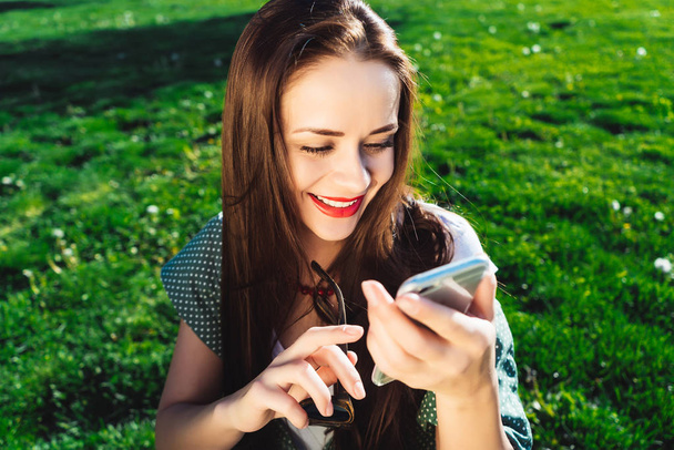 Texting woman,surprised,grass summer background,smiling and looking into the phone - Photo, image