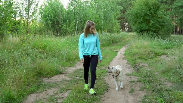Jeune femme marche avec un chien dans la forêt
 - Photo, image