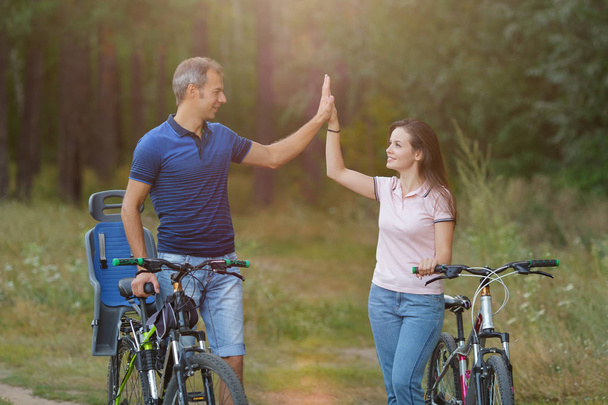 glückliches Paar mit Fahrrädern vergnügt sich im Kiefernwald - Foto, Bild