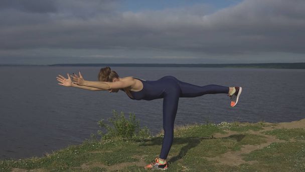 Женщина стоит на одной ноге, тренируется равновесие, йога
 - Фото, изображение
