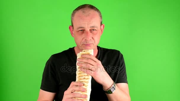 Hombre maduro de mediana edad. Retrato de un hombre maduro come la comida rápida - kebab también llamado giroscopios en frente de la pantalla verde
. - Metraje, vídeo