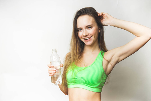 Healthy woman with bottle of water,in a sports green top, poses - 写真・画像